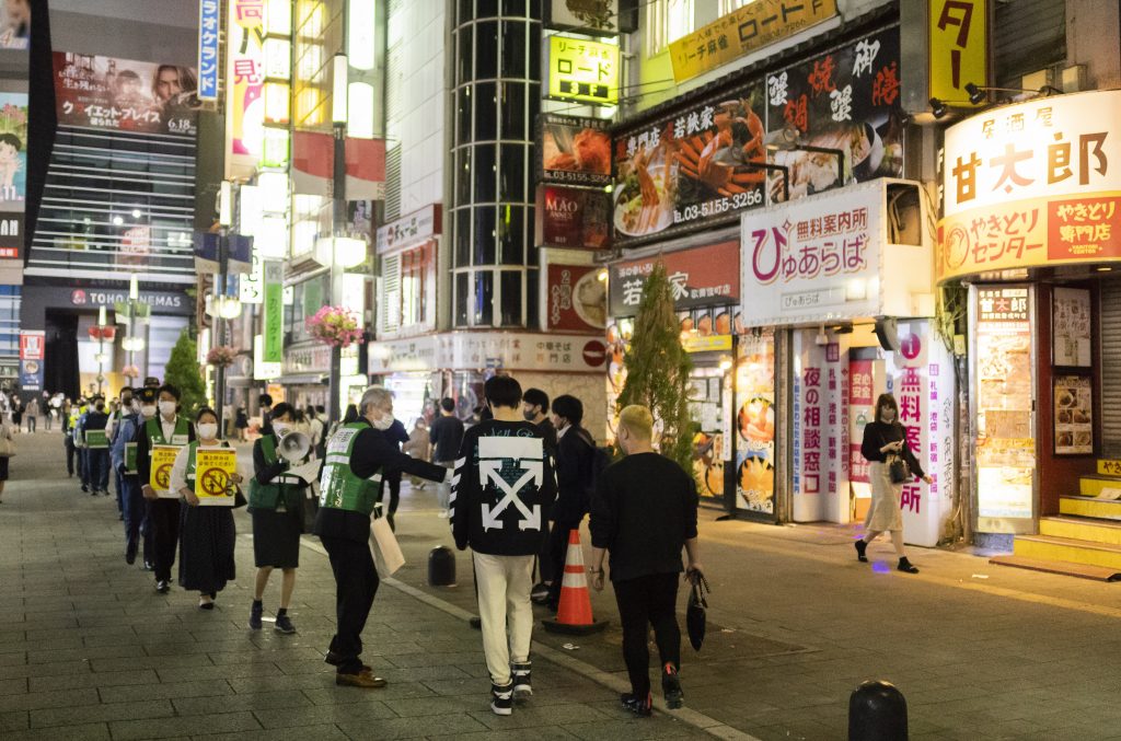 Image Caption : A group of officials from the Tokyo Metropolitan and Shinjuku district governments along with Tokyo police and fire departments walk through the famed Kabukicho neighborhood lined with restaurants and bars as they distribute face masks in Tokyo, May. 28, 2021. (File photo/AP)
