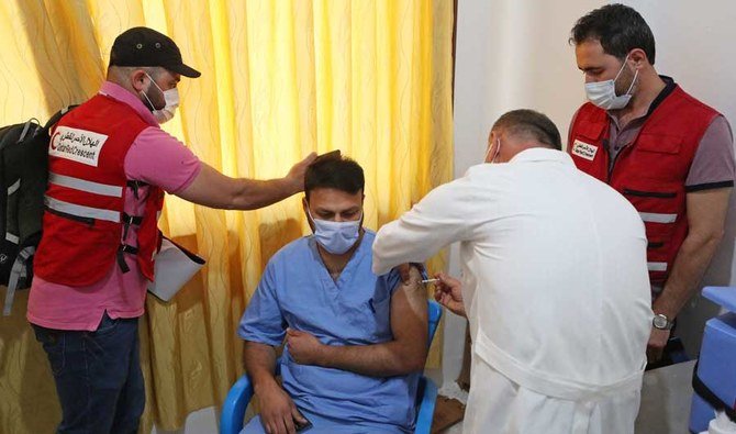 A medical worker receives a dose of the AstraZeneca COVID-19 vaccine in the presence of Qatar Red Crescent personnel at the Ibn Sina Hospital in Syria's northwestern Idlib city on May 1, 2021. (AFP)