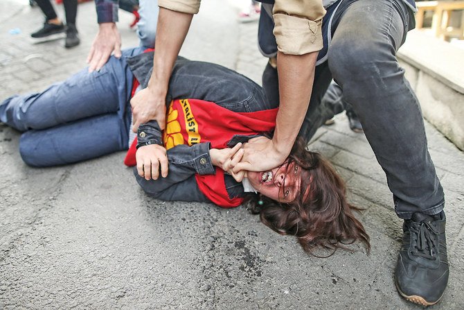 A policeman detains a protester after she and others tried to push through a police barricade toward Taksim Square in Istanbul during Saturday’s May Day protests. (AP)