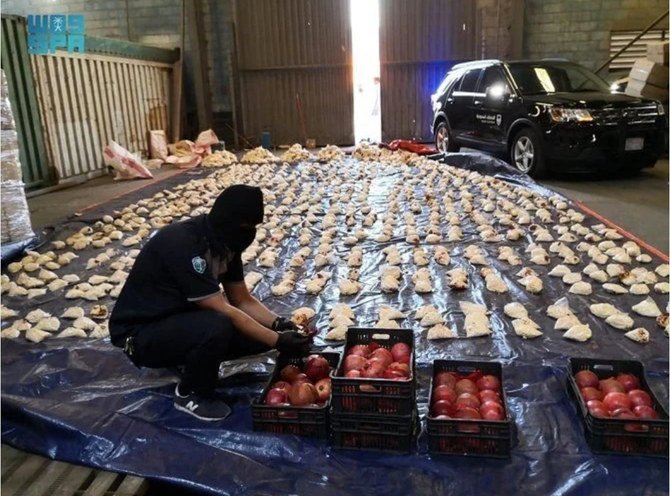 A Saudi anti-narcotics officer arranges a display of Captagon pills and pomegranates shipped from Lebanon. (SPA file photo)