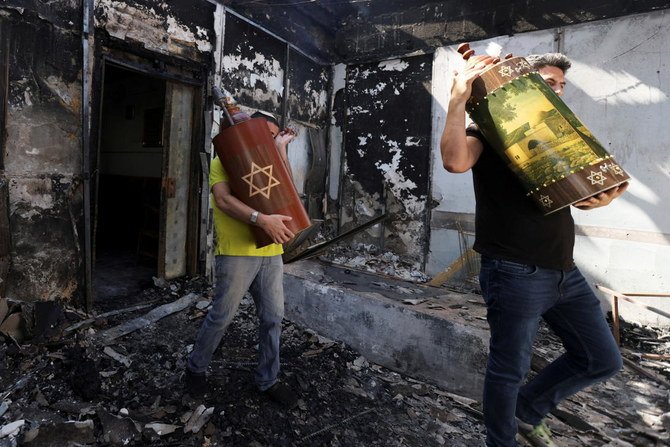 Torah scrolls, Jewish holy scriptures, are removed from a synagogue which was torched during violent confrontations in Lod between Israeli Arab demonstrators and police, amid hostilities between Israel and Gaza. (REUTERS)