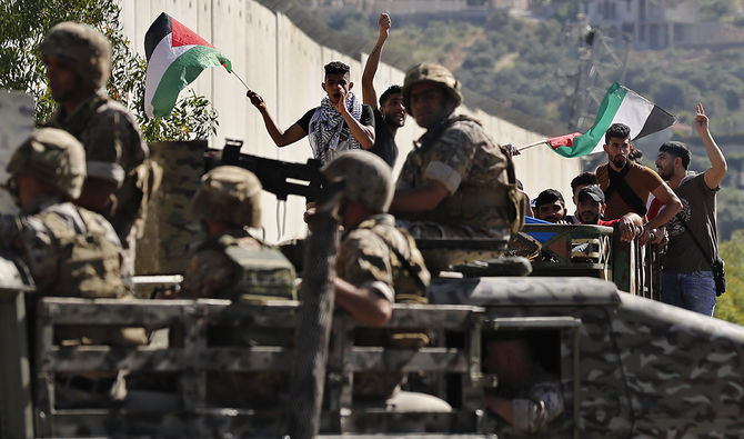 Lebanese army soldiers on their armored vehicles block a road in front Palestinian protesters at the Lebanese side of the Lebanese-Israeli border in the southern village of Kfar Kila, May 15, 2021. (AP)