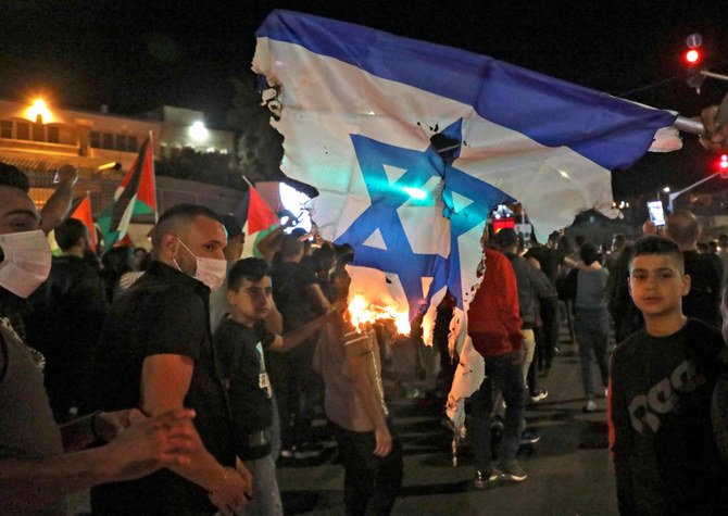 Palestinians burn an Israeli flag in the occupied-West Bank town of Bethlehem on May 15,2021, as they commemorate the Nakba, the 