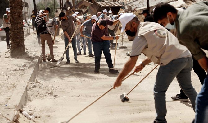 Palestinian volunteers clear rubble and clean a road in Gaza City, on May 29, 2021, more than a week after a ceasefire brought an end to 11 days of hostilities between Israel and Hamas. (AFP)