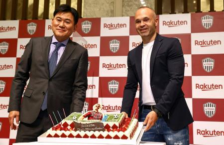 This handout picture released from Japanese professional football club Vissel Kobe on May 11, 2021 shows Vissel Kobe player Andres Iniesta (right) posing with Hiroshi Mikitani (left), chairman and CEO of Rakuten and the football club chairman, as they display a cake to celebrate Iniesta's birthday, at a press conference in Tokyo. (AFP)