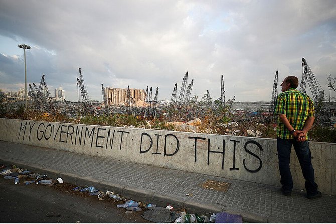 A man stands next to graffiti on Aug. 11, 2020, outside Beirut’s port, in the aftermath of the massive explosion that damaged much of Lebanon’s capital. (Reuters)