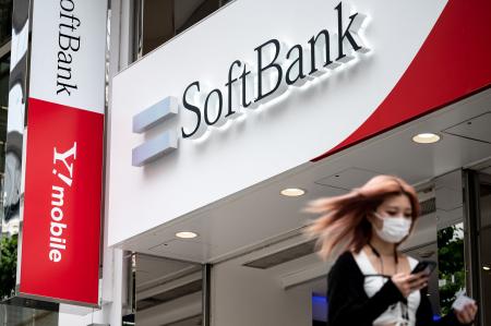 A woman walks past a logo of the SoftBank Group in Tokyo on May 12, 2021. (AFP)