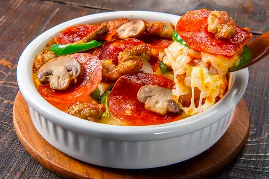 The standard Pizza Rice Bowl Domino Deluxe is made using rice, tomato sauce, onions, peppers, pepperoni, sausage, and mushroom. (Domino’s Pizza Japan)
