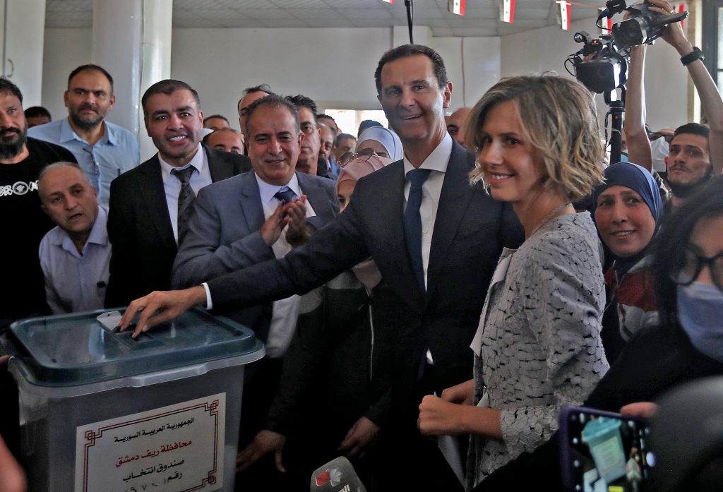 Syrian President Bashar al-Assad (C) and his wife Asma (R) cast their votes at a polling station in Douma, near Damascus on May 26, 2021, as voting began across Syria for an election guaranteed to return Assad for a fourth term in office. (AFP)