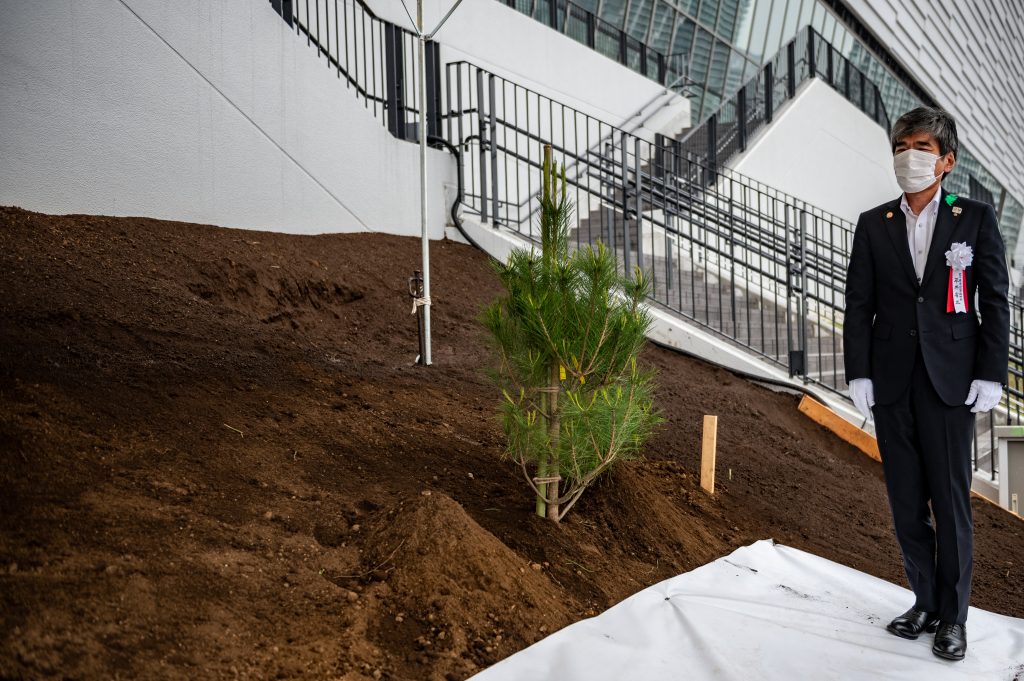 Shozo Hirai, director of the Iwate Prefecture Tokyo Office, stands next to a freshly-planted Japanese red pine to commemorate the reconstruction of disaster-affected areas in Japan, ahead of the Tokyo 2020 Olympics at Ariake Arena in Tokyo on June 6, 2021. (AFP)