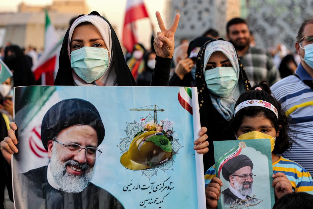 Women supporters of Iran's newly-elected president Ebrahim Raisi hold posters depicting him as they celebrate his victory in Imam Hussein square in the capital Tehran on June 19, 2021. (AFP)