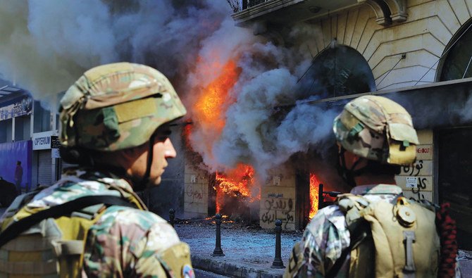 In this April 28, 2020, photo, Lebanese soldiers in the northern city of Tripoli stand guard in front of a bank that was set on fire by anti-government protesters. (AP)