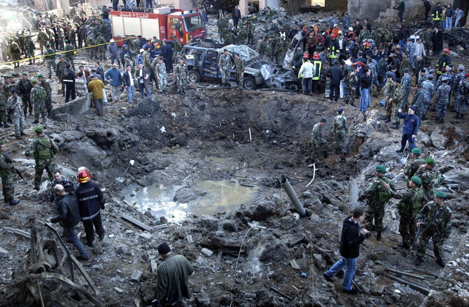 In this Feb. 14, 2005 file photo, rescue workers and soldiers stand around a massive crater after a bomb attack that tore through the motorcade of former Prime Minister Rafik Hariri in Beirut, Lebanon. (File/AP)