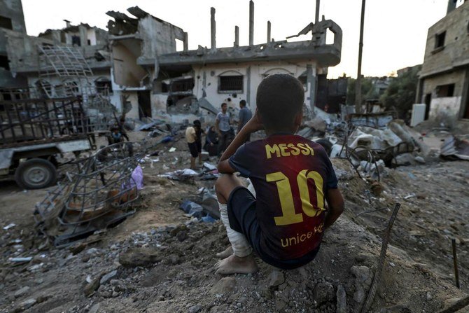 A boy sits near buildings destroyed during recent Israeli strikes in the northern Gaza Strip, more than a week after a ceasefire brought an end to hostilities between Israel and Gaza rulers Hamas. (File/AFP)