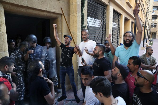 Riot police stand guard as anti-government protesters in Beirut chant slogans against the political leadership they blame for the economic and financial crisis. (AP)