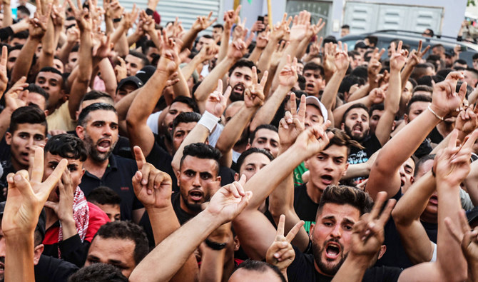 Palestinian men react as the body of Mohammad Said Hamayel, 15, killed Friday in confrontations with Israeli security forces following a demonstration, is carried to his grave in the occupied West Bank on June 11, 2021. (AFP)