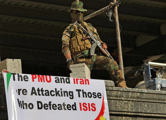 A security guard stands next to placards denouncing Al-Hashd Al-Shaabi as Iraqi Kurds attend a demonstration outside the US consulate in Irbil in 2017. (AFP/File)