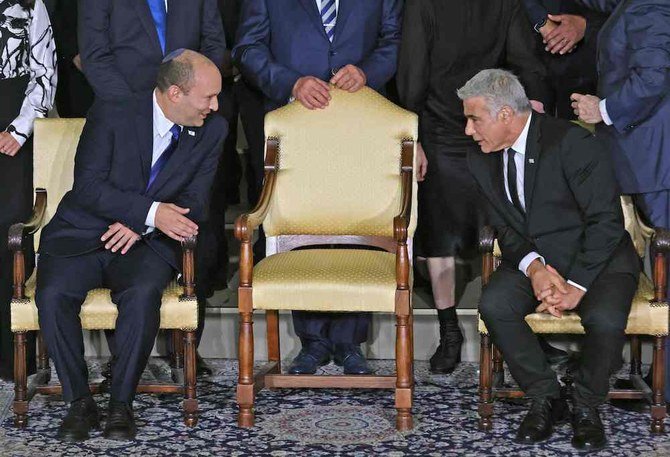 Israeli Prime Minister Naftali Bennett (L) and alternate Prime Minister and Foreign Minister Yair Lapid chat ahead of a photo of the new coalition government. (AFP)