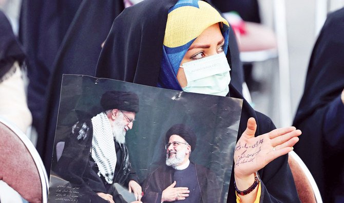 A supporter of Iranian presidential candidate Ebrahim Raisi holds a picture of him with supreme leader Ayatollah Ali Khamenei at an election rally in Tehran. (AFP)