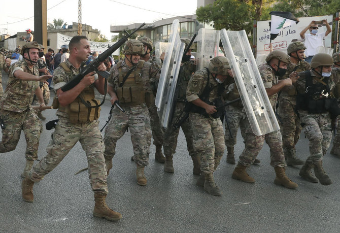 In this September 12, 2020 file photo, a Lebanese army soldier, left, fires in the air to push back the anti-government protesters as other soldiers protect themselves from the stones, during a protest against the Lebanese President Michel Aoun near the presidential palace, in Baabda east of Beirut, Lebanon. (File/AP)