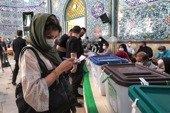 A woman examines a ballot before casting it at a polling station in Iran's capital Tehran on June 18, 2021, during the 2021 presidential election. (File/AFP)