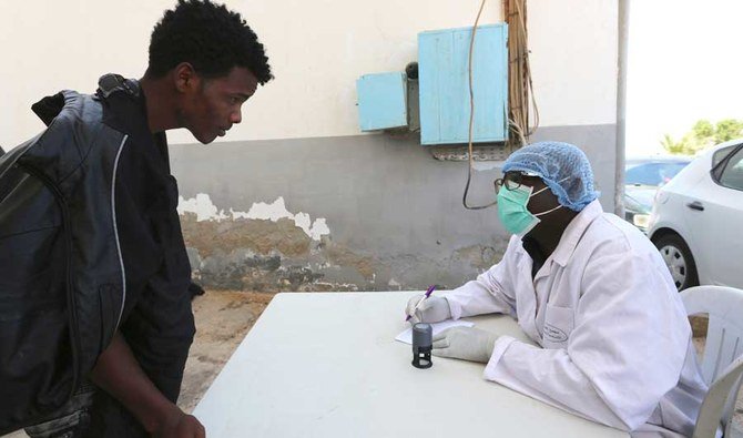A doctor from the International Organization for Migration (IOM) checks a rescued migrant's identity before administering a Coronavirus test, in Ben Guerdane, southern Tunisia, Saturday June 12, 2021. (AP)
