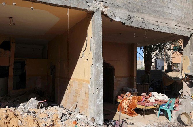 A Palestinian boy and his father sleep in the ruins of their family house which was heavily damaged in Israeli air strikes during the latest Israeli-Palestinian fighting, in Gaza City, on June 25, 2021. (AFP)