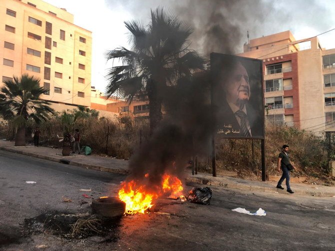 A man walks near a burning fire blocking a road, during a protest against mounting economic hardships, in Beirut, Lebanon June 28, 2021. (Reuters)