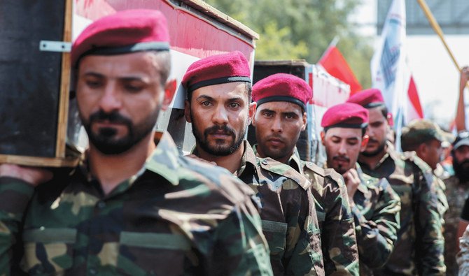 Members of Iraqi Popular Mobilization Forces, during a symbolic funeral in Baghdad on Tuesday, carry the mock coffins of comrades who were killed by US airstrikes. (AFP)