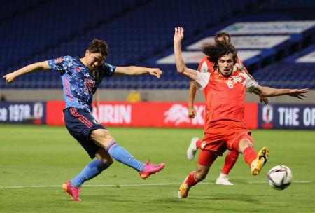 Japan's forward Takuma Asano (left) shoots the ball as Tajikistan's defender Vahdat Hanonov (right) tackles during the FIFA World Cup Qatar 2022 Asian zone group F qualification football match in Suita, Osaka prefecture on June 7, 2021. (AFP)