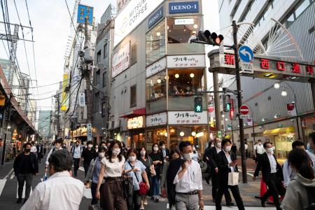 People walk in the street in Tokyo’s Shimbashi area on June 21, 2021, after Japan announced that a virus state of emergency in Tokyo and several other regions was lifted on June 20, just over a month before the Olympics. (AFP)