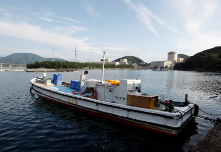 A boat is seen at a fishing port as Kansai Electric Power Co.'s Mihama nuclear power plant is pictured in the background in Mihama town, Fukui prefecture, July 2, 2011.