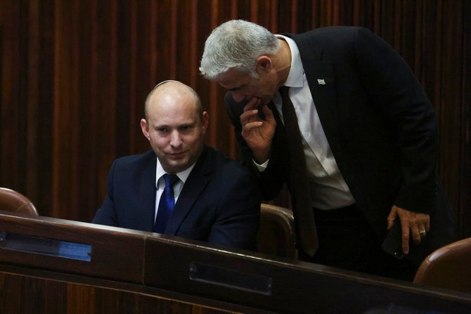 Yamina party leader Naftali Bennett, left, speaks to Yesh Atid party leader Yair Lapid during a special session of the Knesset in Jerusalem on June 2, 2021. (Ronen Zvulun/Pool Photo via AP)