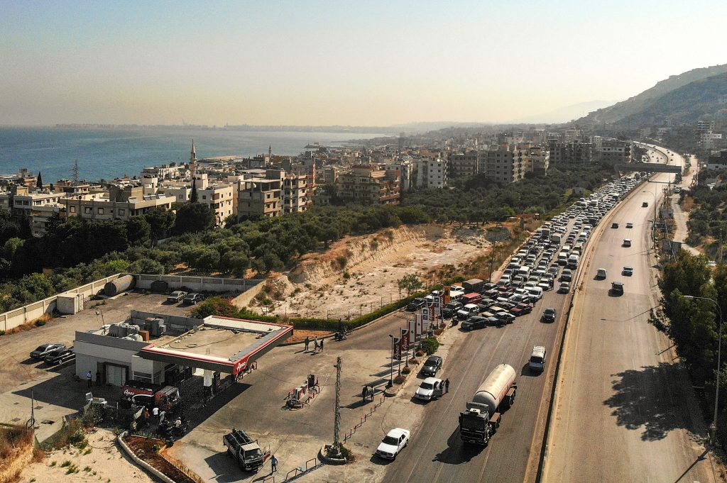 Vehicles on the left lane adjacent to a petrol station queueing-up for fuel as traffic flows through on the Tripoli-Beirut highway at the coastal city of Qalamun, northern Lebanon, amidst severe fuel shortages, July. 1, 2021. (AFP)