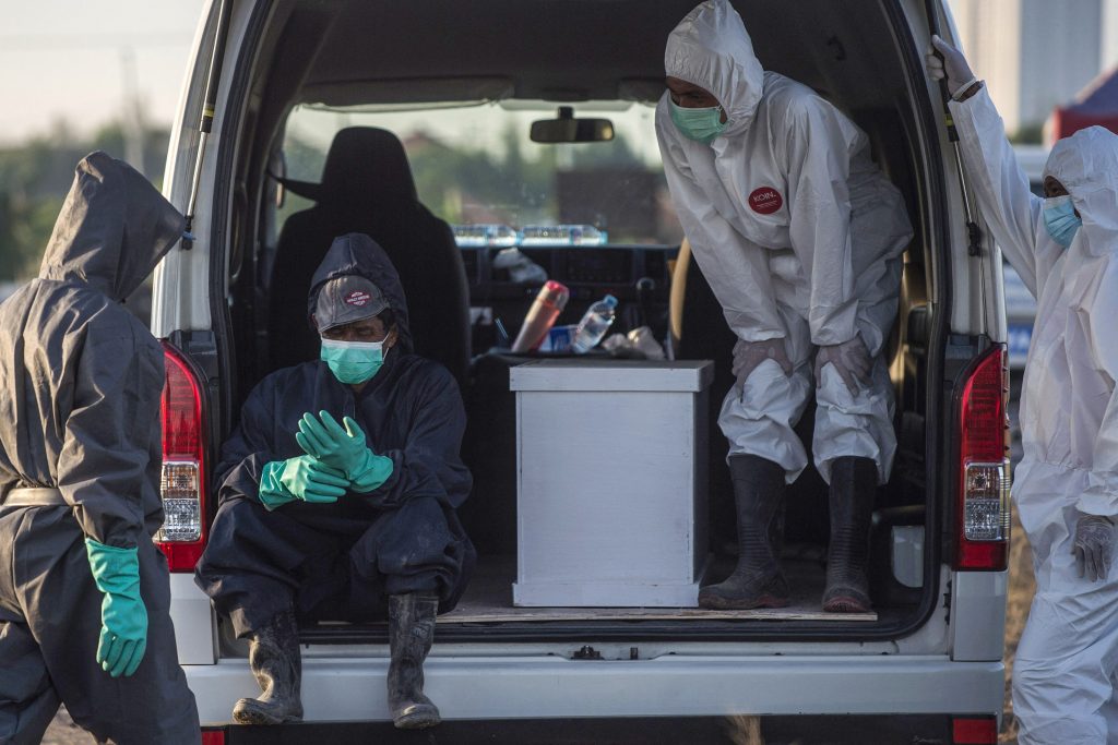 Funeral workers take a break at the burial site for the Covid-19 coronavirus victims at Keputih cemetery in Surabaya, East Java on July 17, 2021. (AFP)