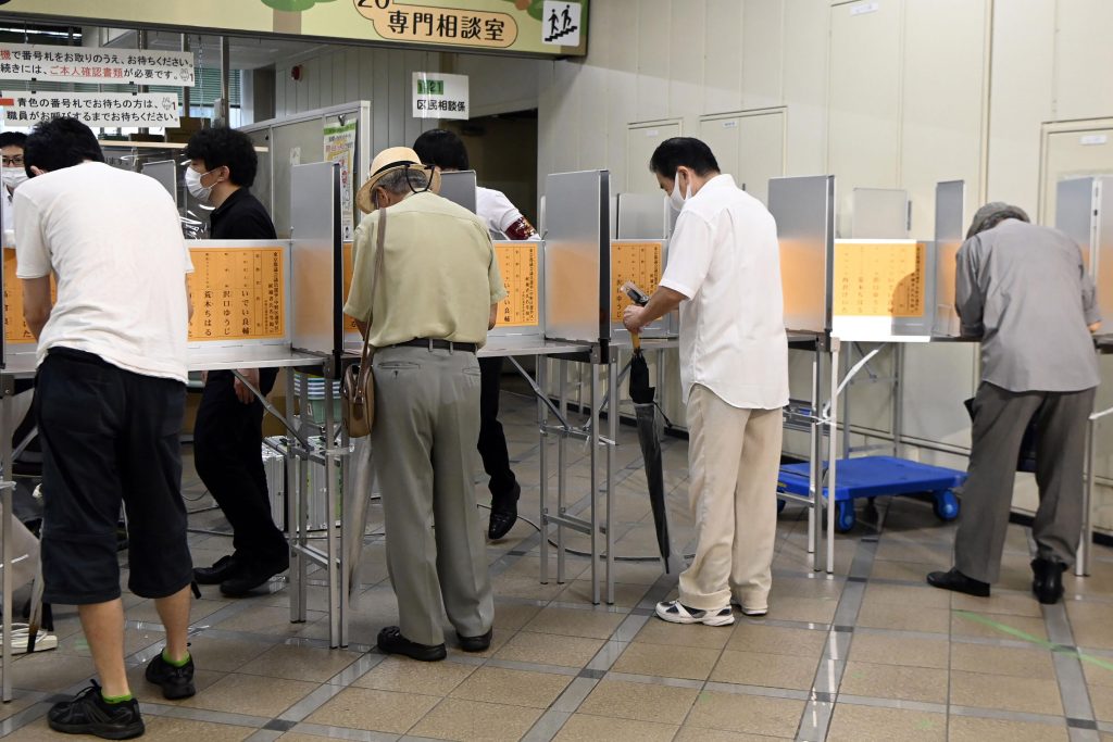 Voters fill in their ballots at a polling station in Tokyo Sunday, July 4, 2021. Voters in Japan's capital are electing the Tokyo city assembly Sunday amid worries about health risks during the Olympics, opening in three weeks, as coronavirus cases continue to rise. (Kyodo News via AP)