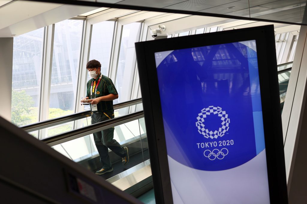A man wearing a face mask walks past Tokyo 2020 Olympic Games signage at the Main Press Center during the coronavirus disease (COVID-19) outbreak in Tokyo, Japan, July 16, 2021. REUTERS/Thomas Peter