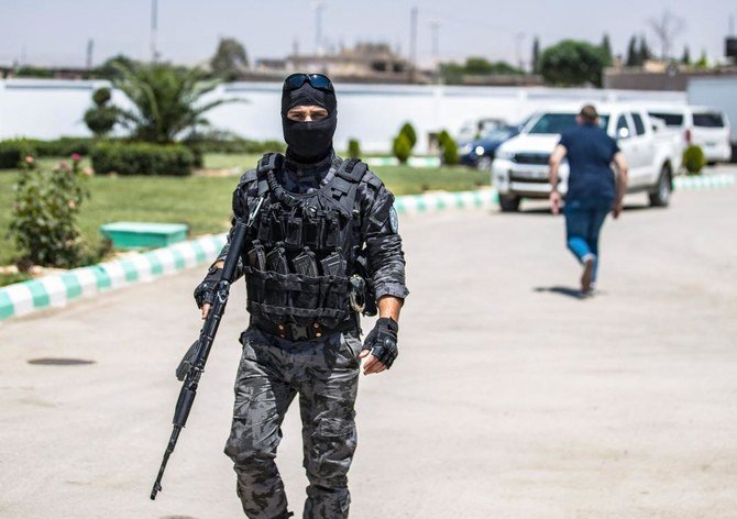 A member of Kurdish securiy forces stands guard as Syrian Kurdish authorities set out to hand over Russian orphans born to parents linked to Daesh to a Russian delegation for repatriation in Qamishli. (AFP)