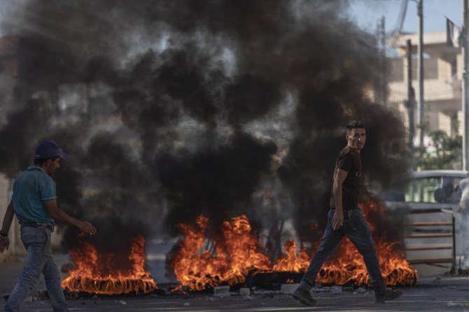 Palestinians burn tires and clash with Israeli army troops securing the parameter of Palestinian American Muntasser Shalaby's house that was demolished with controlled explosions. (AP)