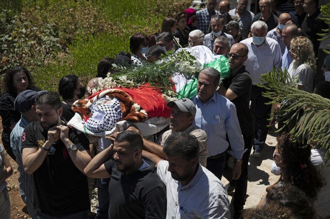 Palestinian mourners carry Suha Jarrar daughter of Khalida Jarrar, who is imprisoned in an Israeli jail, during her funeral, in Ramallah on Tuesday. Activists and human rights groups urged Israel to allow Jarrar to attend the funeral. (AP)