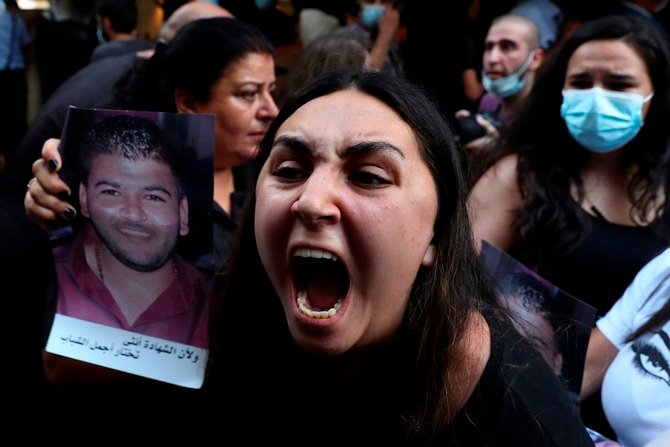 A woman whose brother was killed during last year's massive blast at Beirut's seaport, holds his portrait as she chants slogans during a protest outside caretaker Interior Minister Mohamed Fehmi’s home in Beirut Tuesday. (AP)