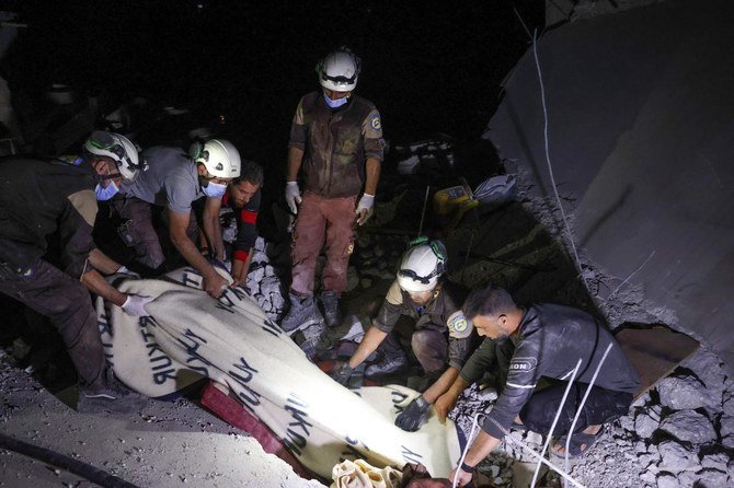 Members of the Syrian Civil Defence (White Helmets) cover the body of a woman with a blanket, as they remove it from the rubble of a house hit by regime artillery fire in the village of Ehsim, in the country's last major rebel bastion of Idlib in the northwest, early on July 18, 2021. (AFP)