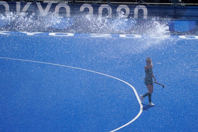 An Australia women's field hockey player walks beneath a sprinkler during a training session ahead of the the 2020 Summer Olympics on July 23, 2021, in Tokyo. (AP Photo/John Locher)
