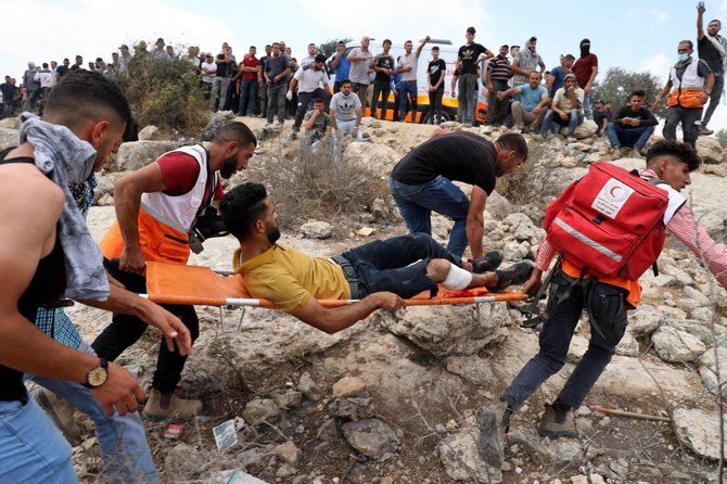 Medics evacuate an injured Palestinian protester amid clashes with Israeli forces during a demonstration in Beita near Nablus city in the occupied West Bank, to denounce Israel’s outpost of Eviatar on a nearby hill. (AFP)