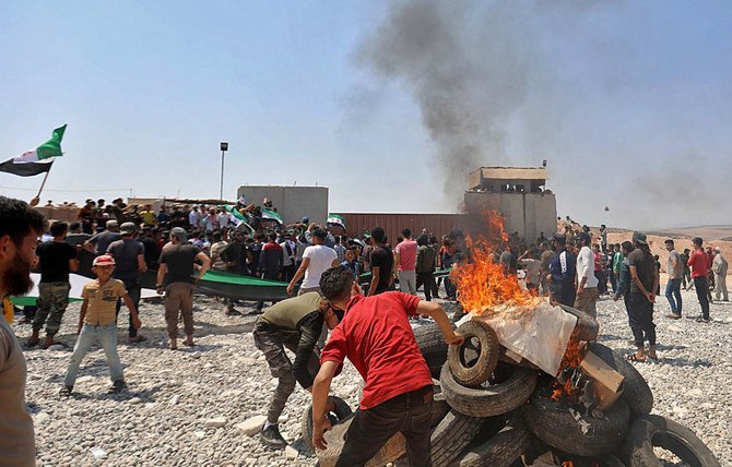 Syrians burn tyres as they protest in front of a Turkish military outpost during a demonstration against Turkey's perceived inaction over the latest Syrian regime attacks, in the town of Maataram near Ariha in the rebel-held northwestern Idlib province, on July 23, 2021. (File/AFP)