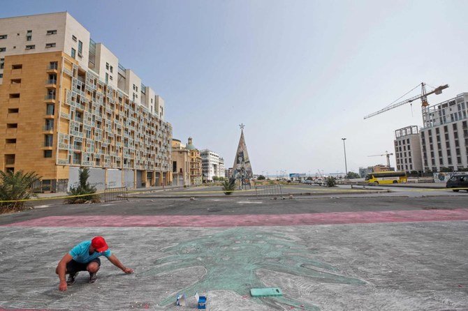 Lebanese painter Giovanni Basil draws what he hopes will become the largest Lebanese flag drawn with chalk, on Matyr's Square in downtown Beirut, just opposite of the al-Amin Mosque on July 25, 2021. (AFP)