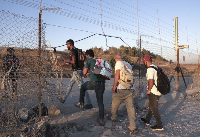 Above, Palestinian workers cross illegaly into Israeli areas through a hole in Israel’s barrier fence near the Mitar checkpoint and the village of Al-Dahriya. (AFP)