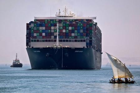 This picture on July 7, 2021 shows a view of the Panama-flagged MV 'Ever Given' container ship sailing near a felucca along Egypt's Suez Canal near the canal's central city of Ismailia. Megaship the MV Ever Given, which had blocked the Suez Canal for six days in March, weighed anchor on July 7 after Egyptian authorities and the Japanese owner agreed a compensation deal. (AFP)