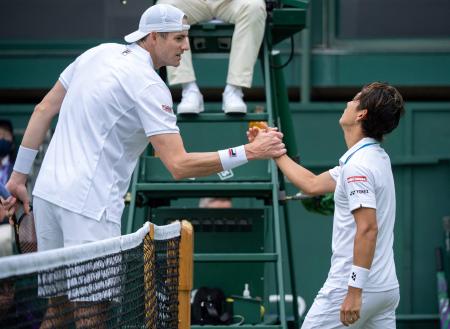 Japan's Yoshihito Nishioka (right) shakes hands after winning against US player John Isner during their men's singles first round match on the third day of the 2021 Wimbledon Championships. (AFP)