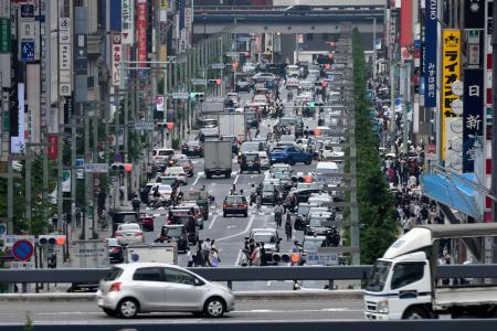 Vehicles and pedestrians move through a street in Tokyo's Ginza shopping district on July 7, 2021. (AFP)